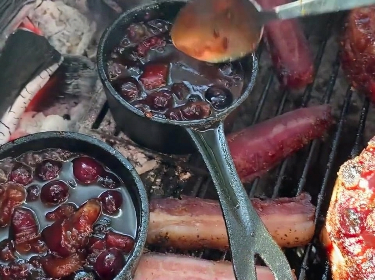 Polewanie faszerowanego koszyczka na grillu gęstym sosem borówkowym BBQ prosto z małego żeliwnego rondelka.
