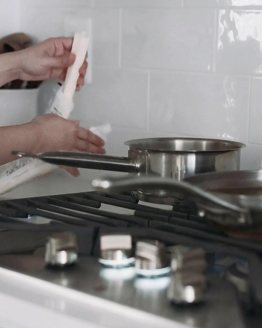 Garnek z wodą na kuchence z gotującym się makaronem udon.