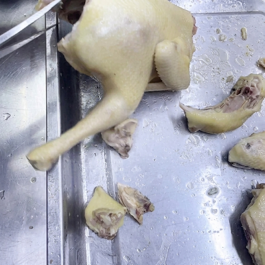 Nożyce kuchenne tnące ugotowanego kurczaka na stalowej powierzchni.