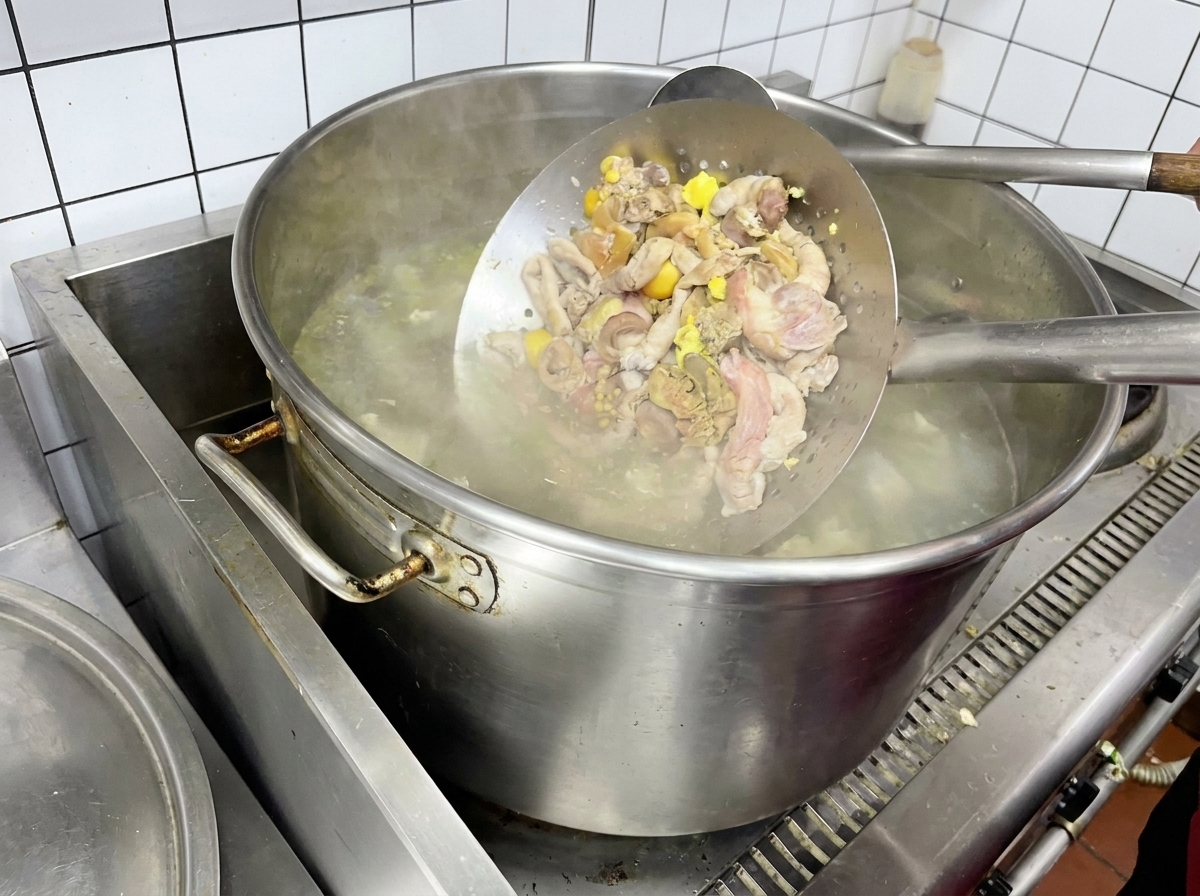 Podroby drobiowe blanszowane w metalowym sitku nad wrzątkiem.