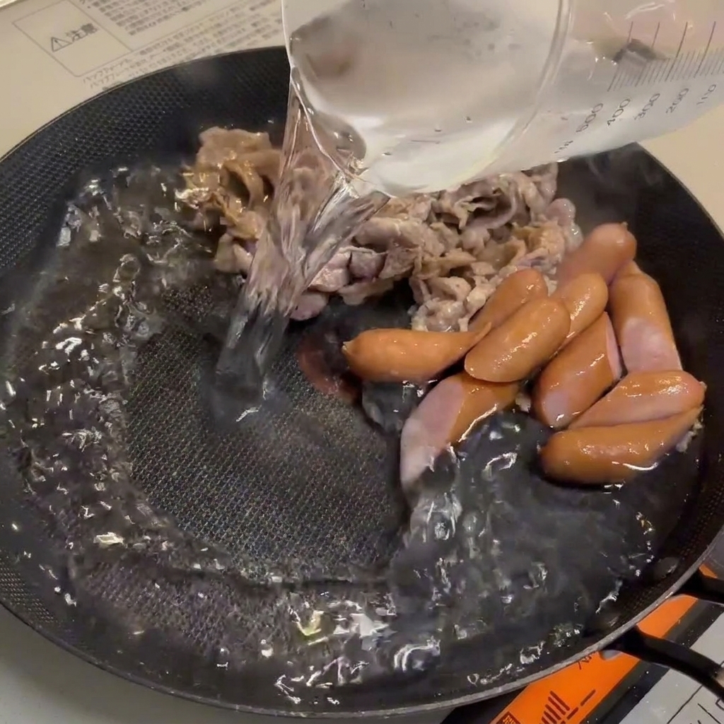 Woda wlewana na patelnię, tworząca bazę bogatego bulionu.