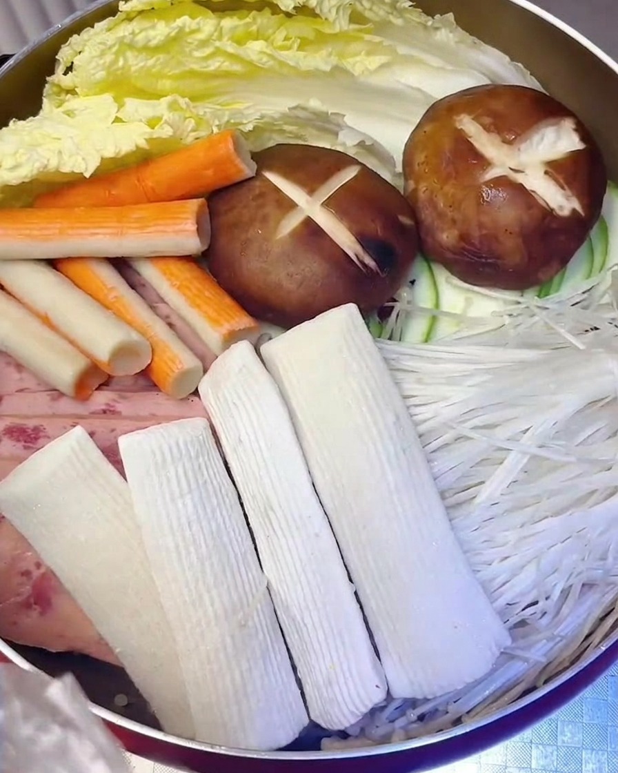 Ciastka rybne i paluszki krabowe ostrożnie dodawane do garnka obok mięsa i warzyw.