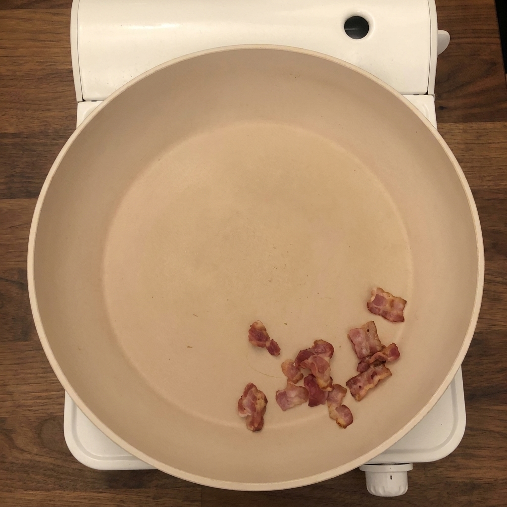Posiekana cebula i seler dodawane na patelnię do chrupiącego boczku.