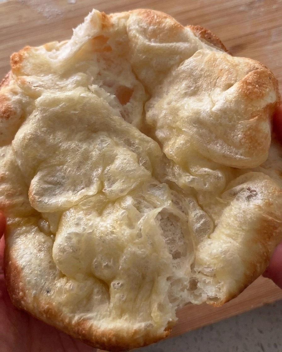 Świeżo upieczony i zarumieniony złożony chlebek do pizzy, delikatnie otwierany.