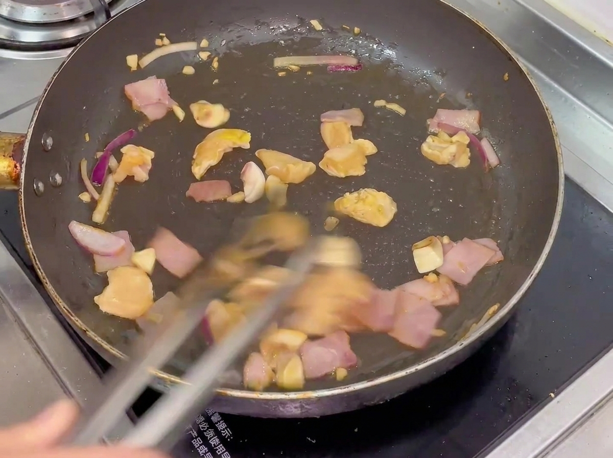 Kurczak, boczek, pieczarki i cebula smażone na patelni.