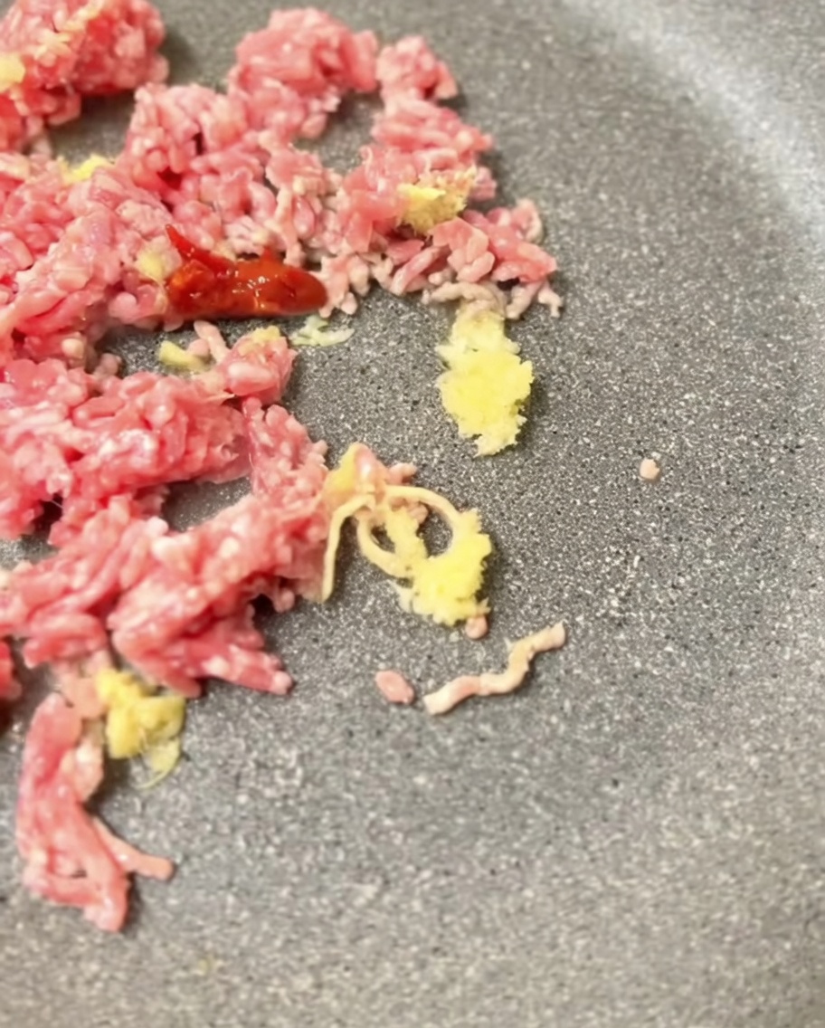 Pasta miso mieszana z podsmażoną wieprzowiną na patelni.