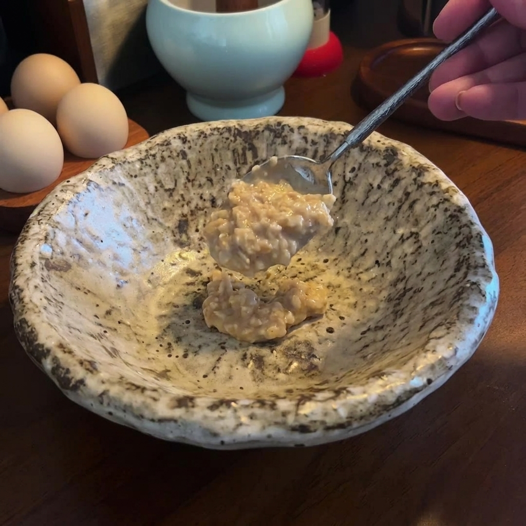 Łyżka gęstej pasty miso i sezamu dodawana do czystej miski serwującej.