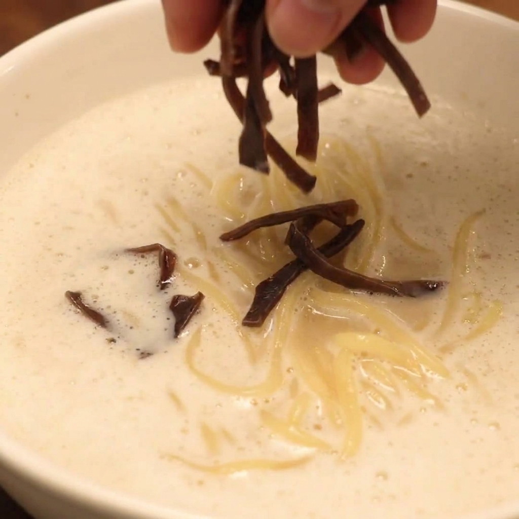 Gotowa miska ramenu Chicken Paitan z chashu, grzybami i warzywami.