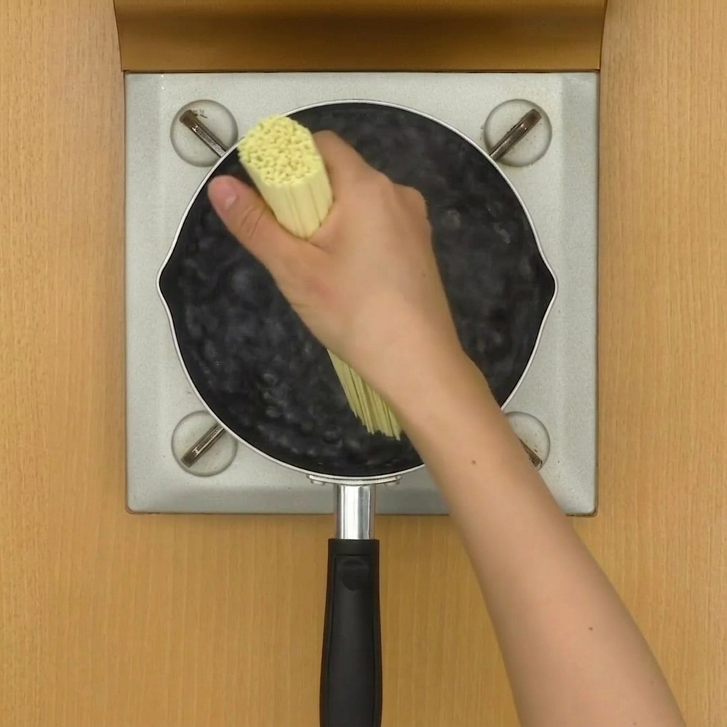 Makaron ramen gotujący się w wodzie, mieszany pałeczkami.