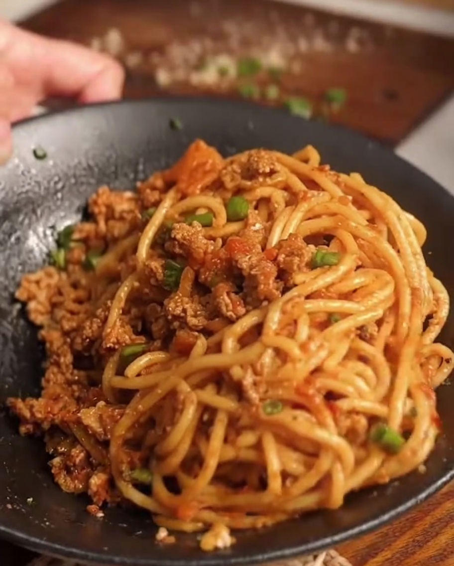 Ugotowane spaghetti przekładane do patelni z sosem.