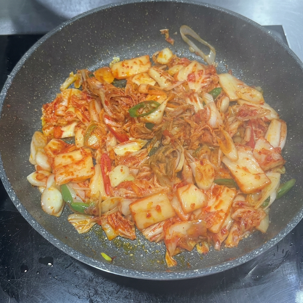 Pasta chili, sos sojowy i cukier dodawane do patelni z kimchi.