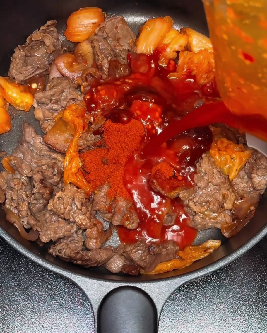 Woda wlewana do patelni z przyprawioną mieszanką wołowiny i kimchi.