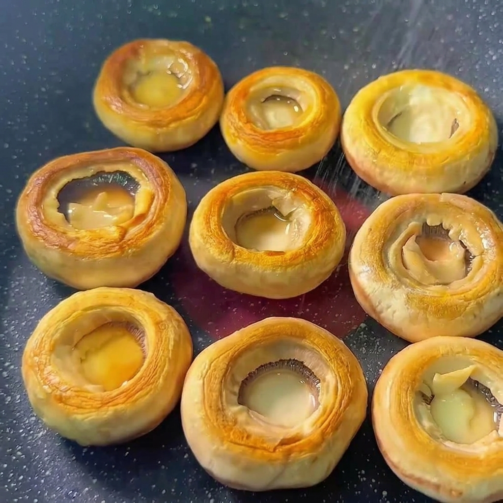 Pieczarki na patelni posypywane solą i pieprzem.