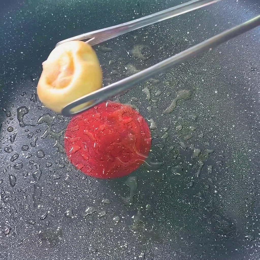 Pieczarki nadziewane krewetkami smażące się na patelni.