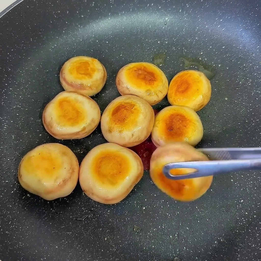 Faszerowane pieczarki smażone na patelni podczas odwracania.