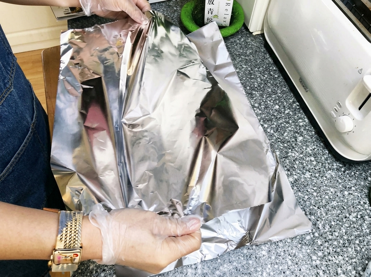 Dłonie ciasno zawijające folię aluminiową wokół żeberek.