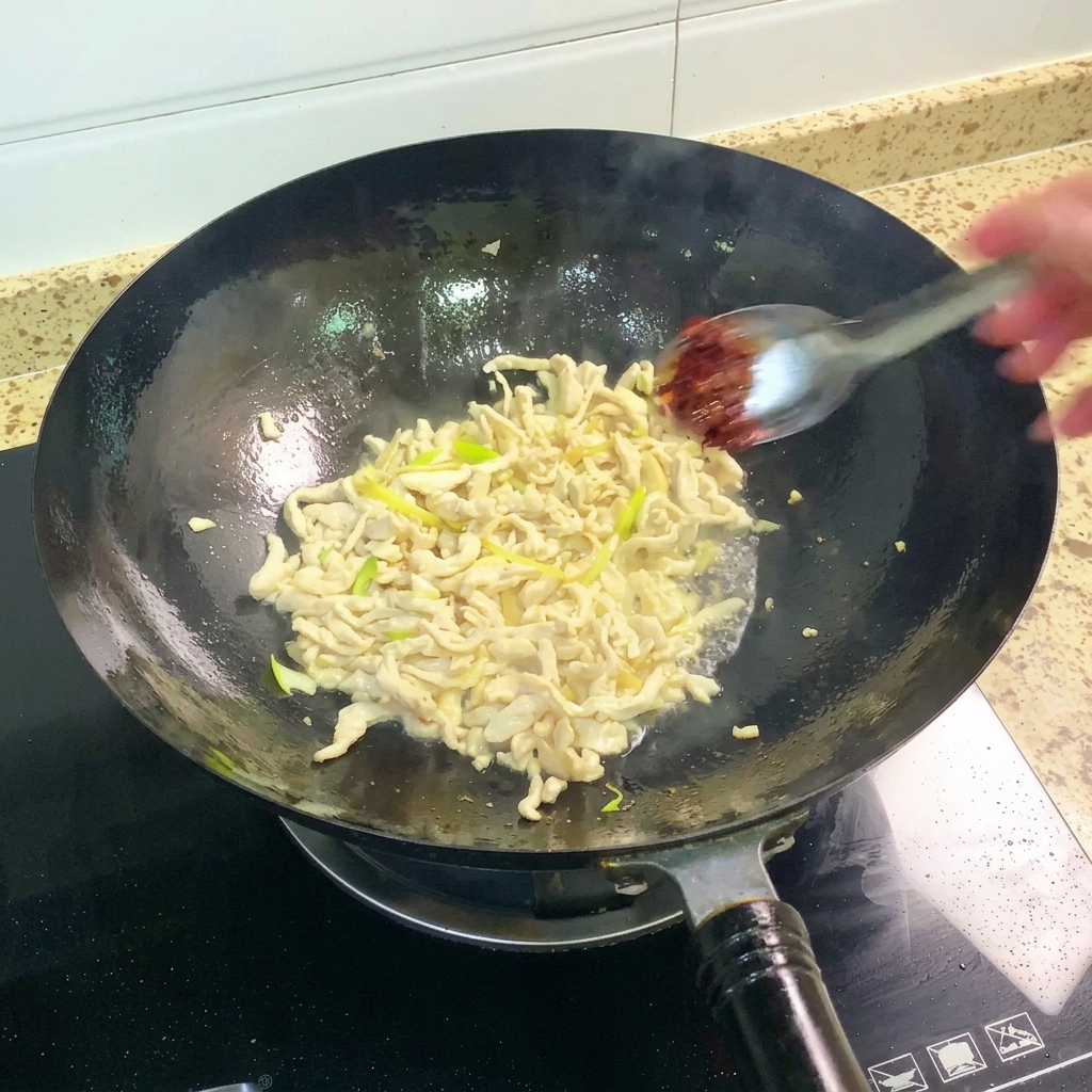 Pasta z bobu Pixian dodawana do woka i mieszana z kurczakiem.