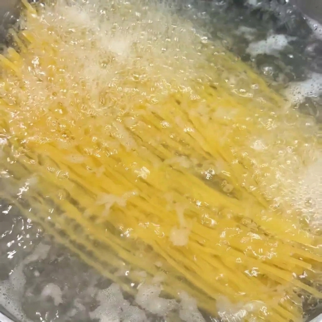 Makaron spaghetti gotujący się w garnku z mocno wrzącą wodą.