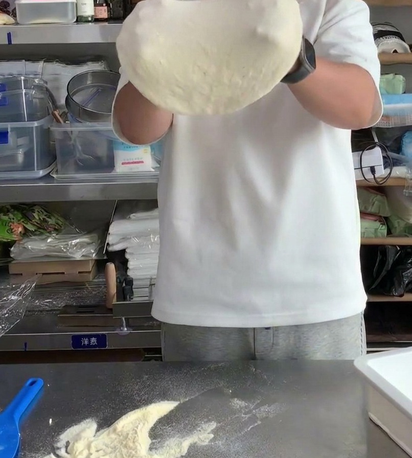 Ciasto na pizzę rozciągane na kłykciach, aby zwiększyć średnicę i pocienić środek.