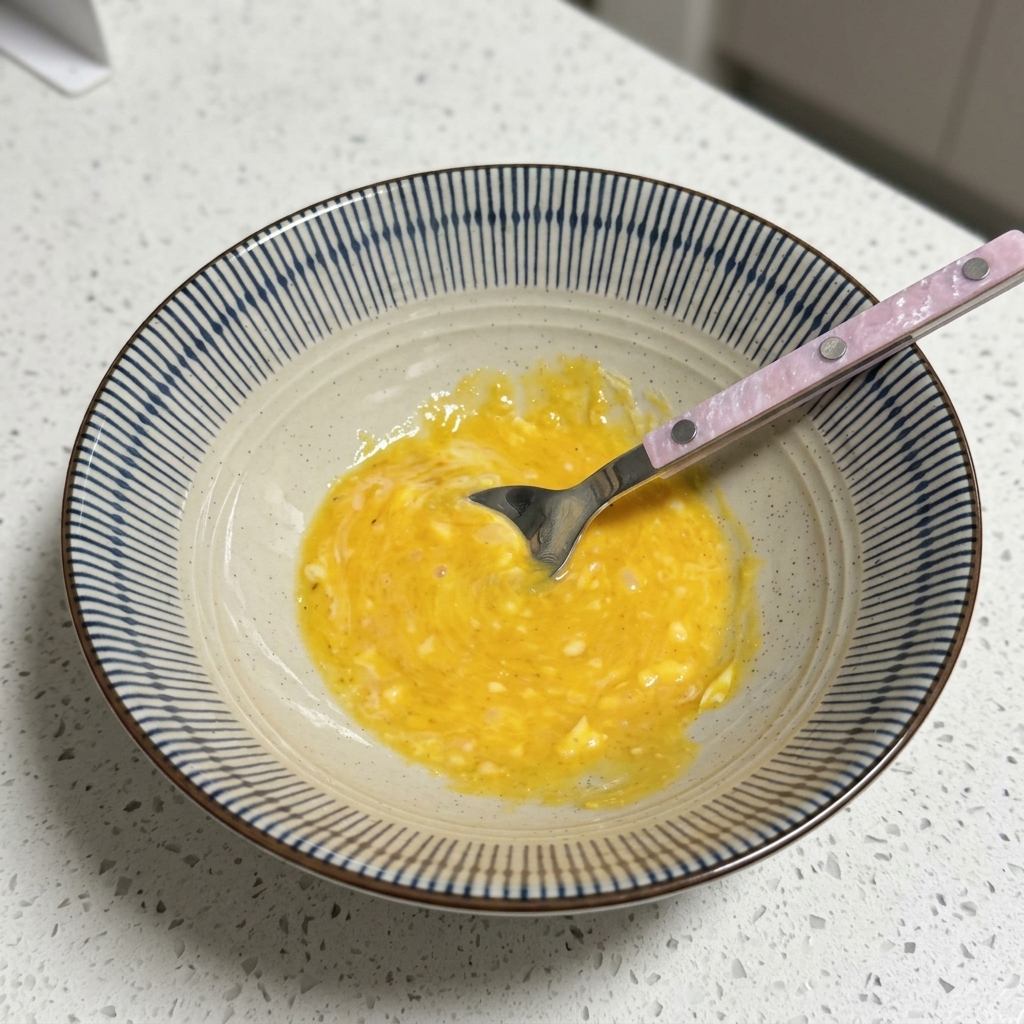 Miska z żółtą, kremową bazą wywaru mieszaną łyżką.