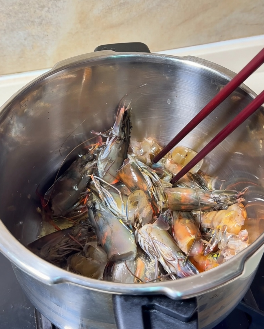 Głowy i skorupki krewetek smażone w garnku, zmieniające kolor na jaskrawo pomarańczowy.