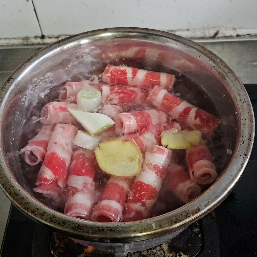 Roladki wołowe gotujące się w garnku z przyprawami i winem.