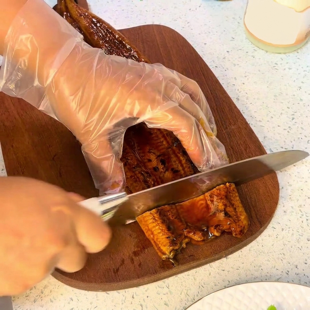 Nóż krojący kawałek grillowanego węgorza na drewnianej desce do krojenia.