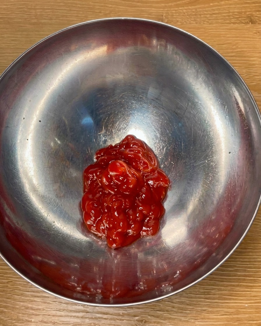 Ketchup i przyprawy mieszane w metalowej misce w celu stworzenia aromatycznego sosu.