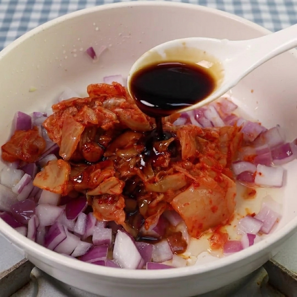Sos sojowy, cukier i ostra pasta gochujang dodawane do mieszanki kimchi z cebulą.