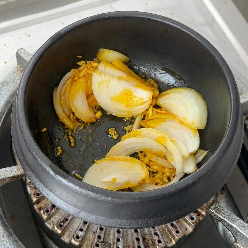 Hojne porcje posiekanego kimchi i plasterki czerwonej papryki mieszane w garnku.