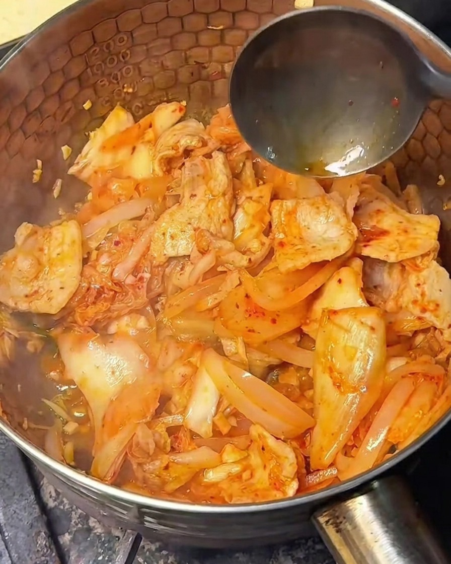 Jasny sos sojowy wlewany do podsmażonego kimchi z boczkiem.