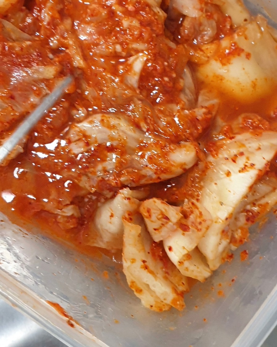 Szczypce wkładające kawałki sfermentowanego kimchi do gotującego się garnka.