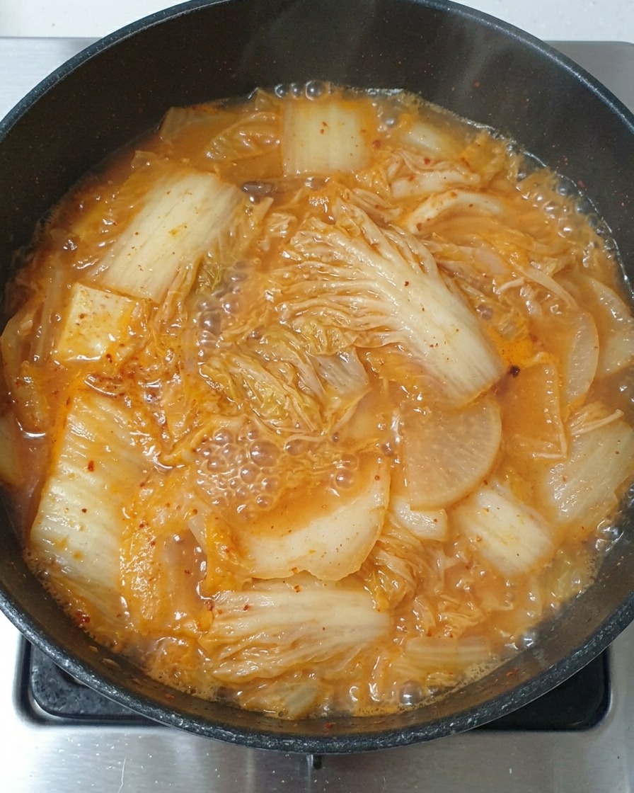 Łyżka jasnego sosu sojowego wlewana do gotującego się gulaszu kimchi.
