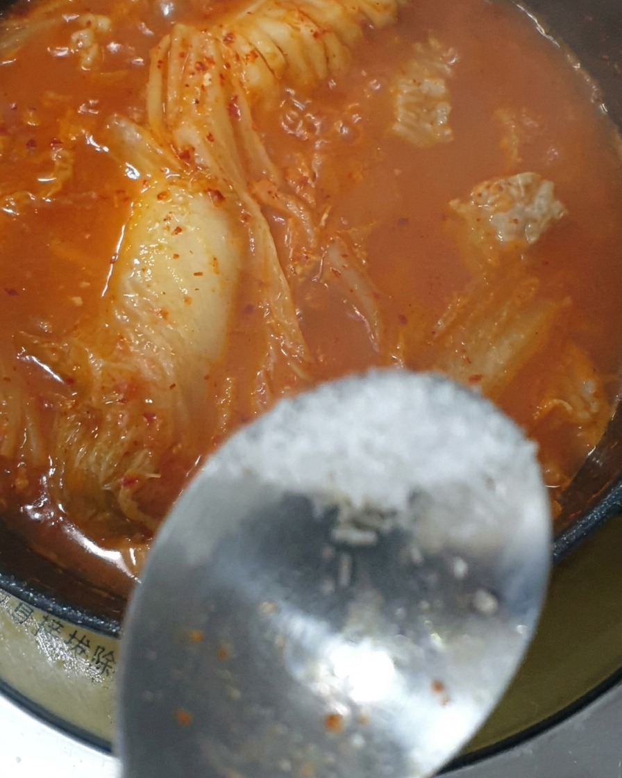 Łyżeczka przypraw dodawana do gotującego się czerwonego gulaszu kimchi.