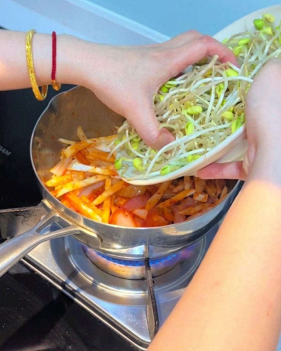 Świeże kiełki fasoli układane na wierzchu mieszanki kimchi i grzybów.