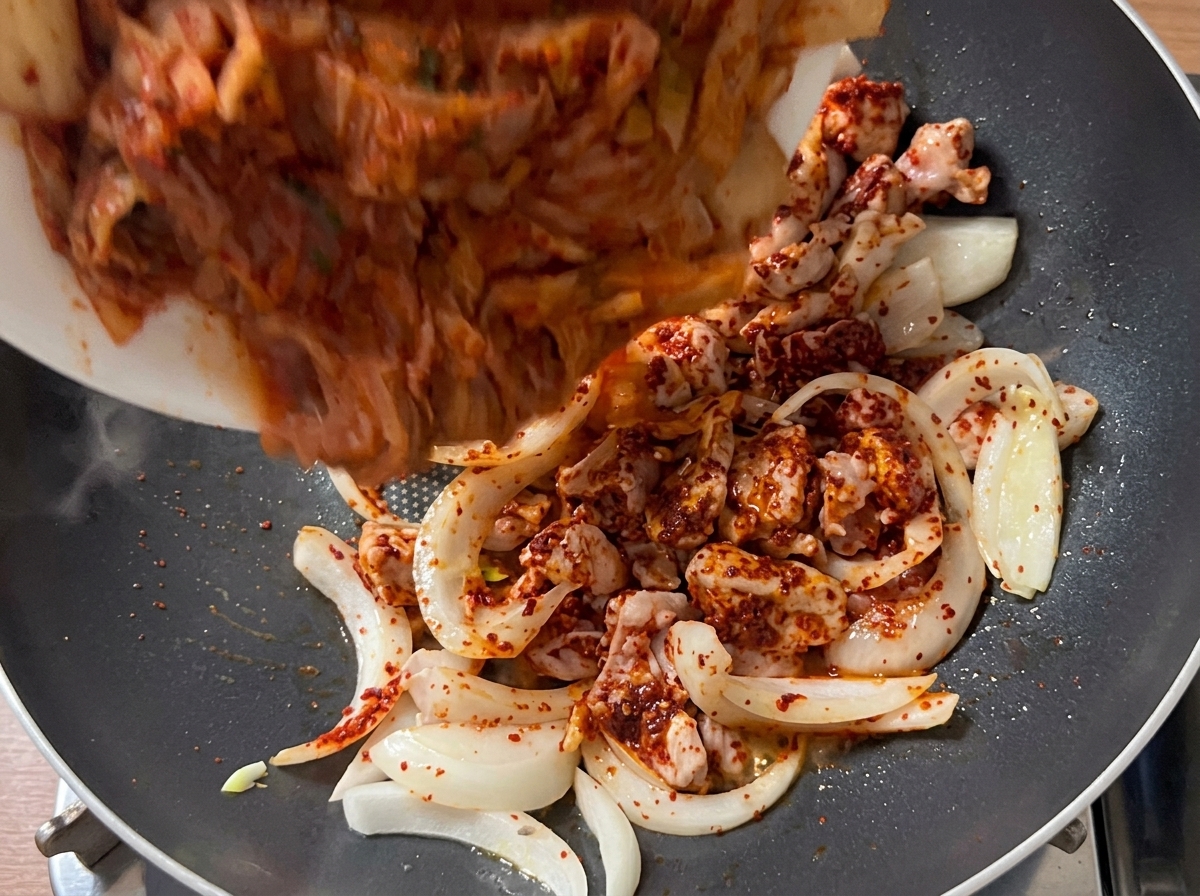 Kawałki kimchi dodawane do podsmażonej wieprzowiny i cebuli.