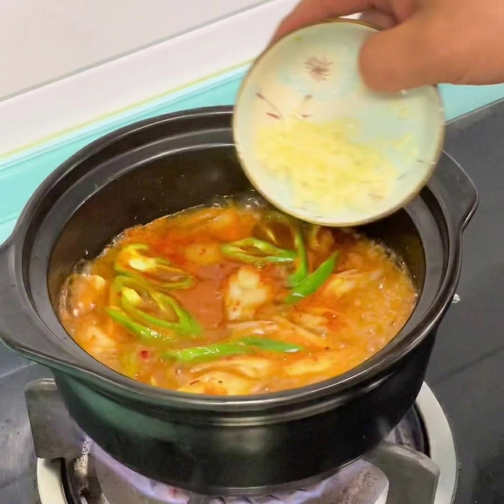 Drobno posiekany czosnek dodawany do gotującego się koreańskiego gulaszu z miękkiego tofu.