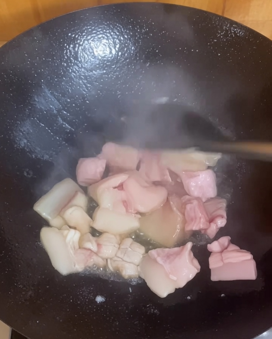 Kawałki boczku skwierczące i rumieniące się w gorącym woku.