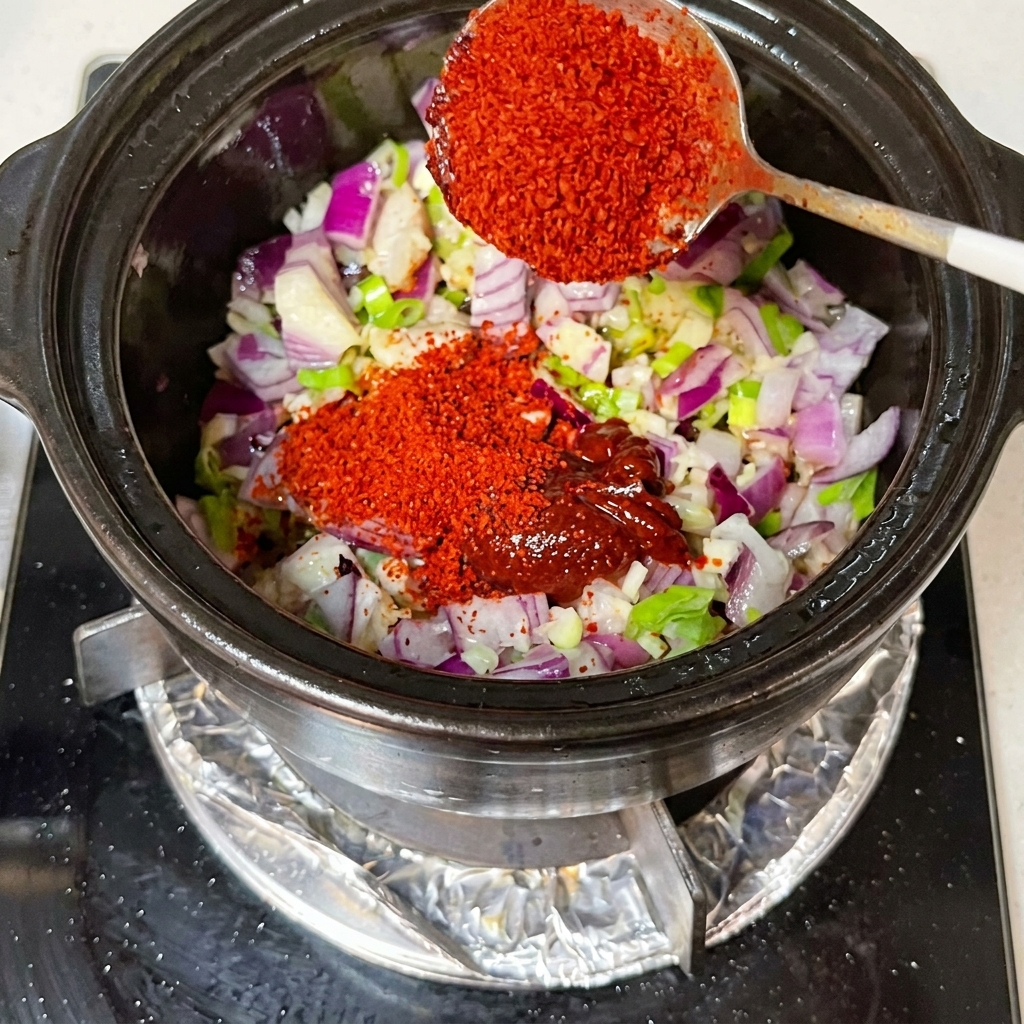 Sos sojowy i kimchi mieszane w garnku z cebulą i aromatami.
