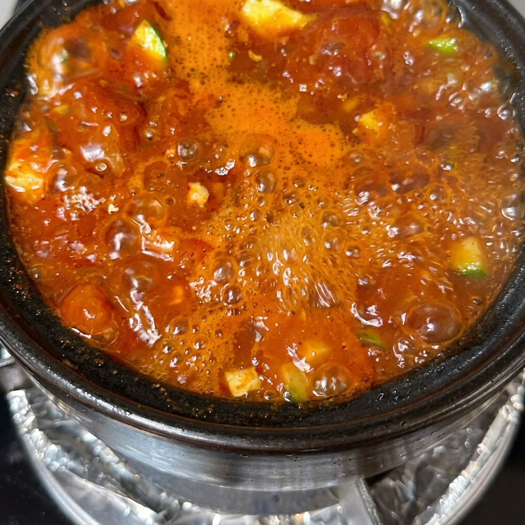 Gotowy garnek zupy tofu udekorowany pokrojoną zieloną cebulką i papryczkami chili.