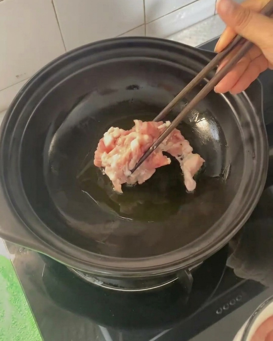 Plastry boczku dodawane pałeczkami do gorącego glinianego garnka.
