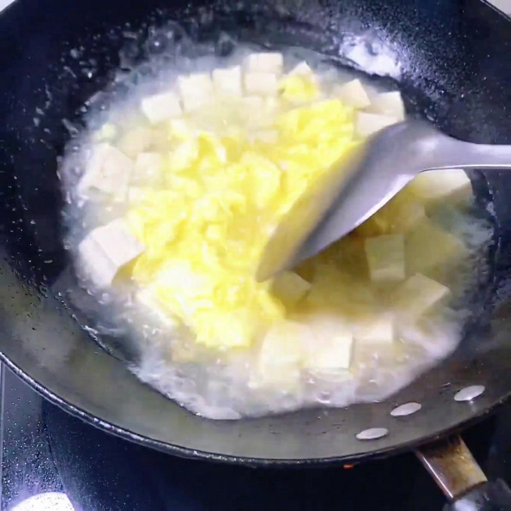 Świeże małże wrzucane do patelni z wywarem i tofu.