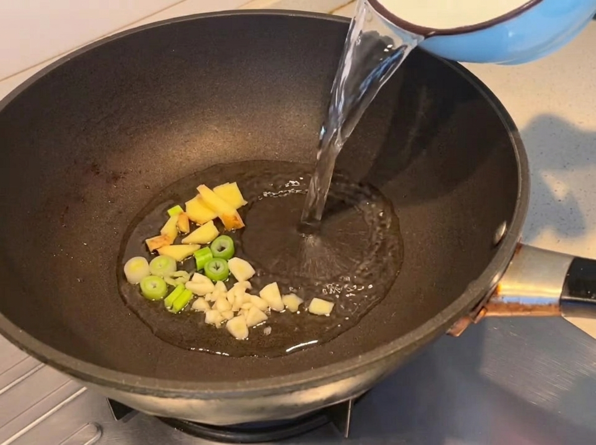 Woda wlewana do patelni z podsmażonymi aromatami.
