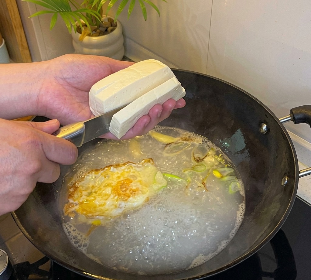 Tofu krojone w kostkę bezpośrednio do wrzącego wywaru.