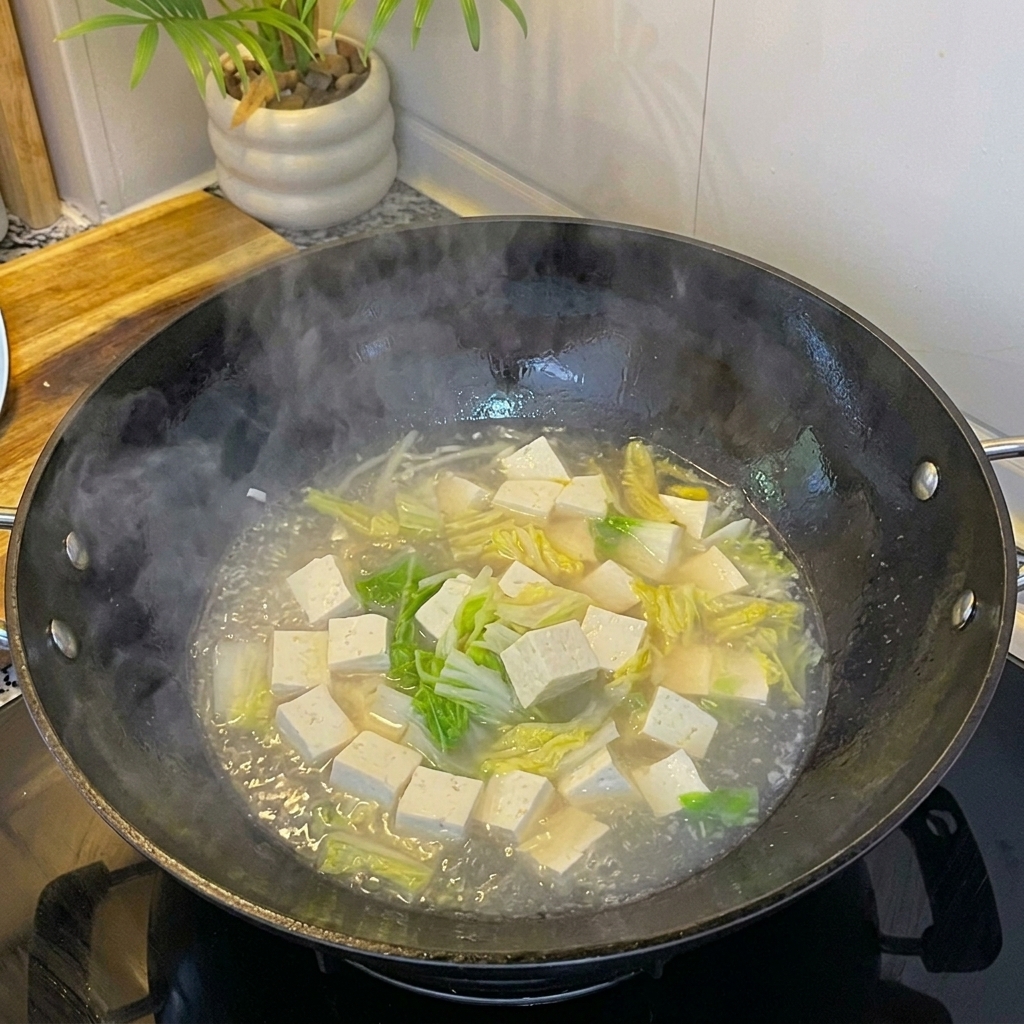 Świeże białe małże dodawane do gotującej się zupy z tofu i jajkiem.
