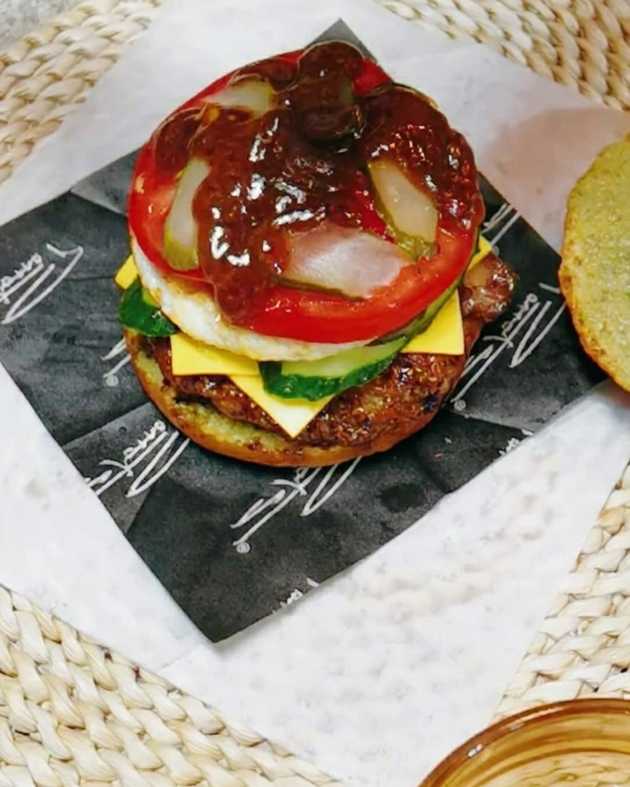 Zbliżenie na składanie burgera skrapianego ciemnym, wytrawnym sosem na bazie teriyaki z dodatkiem soku z cytryny.