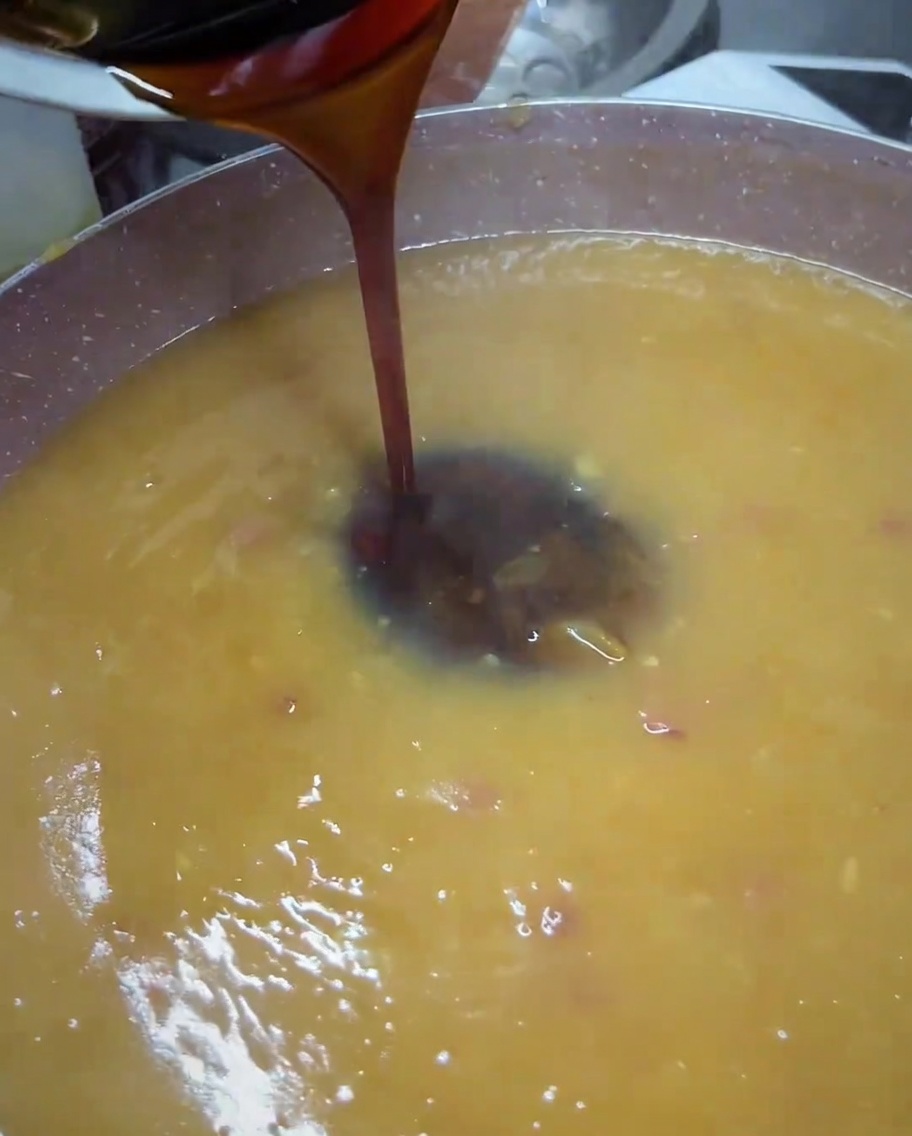 Ciemny sos teriyaki przelewany z małej miseczki na patelnię z blendowanym złocistobrązowym sosem.