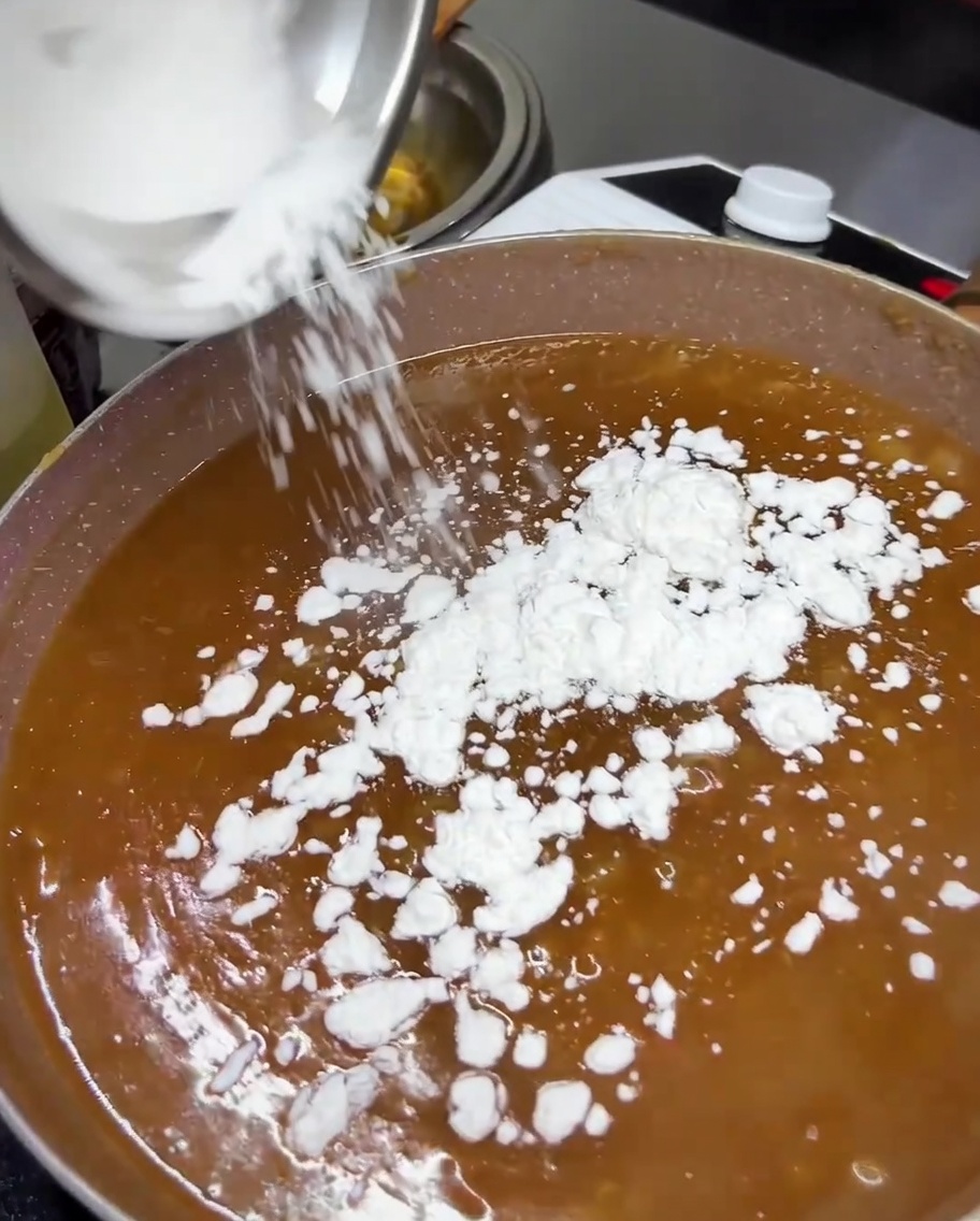 Skrobia z tapioki dodawana do gotującego się sosu teriyaki na patelni.