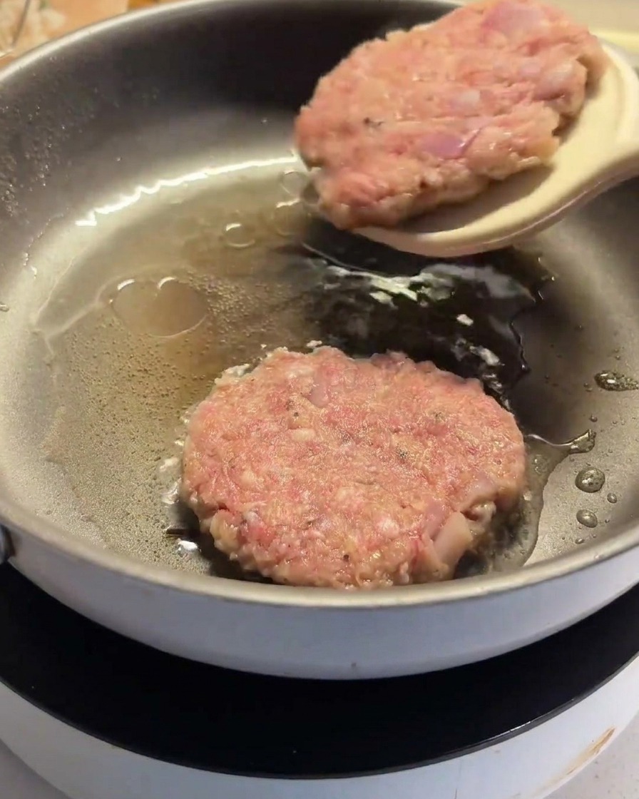 Łopatka odwracająca częściowo usmażony kotlet na patelni.