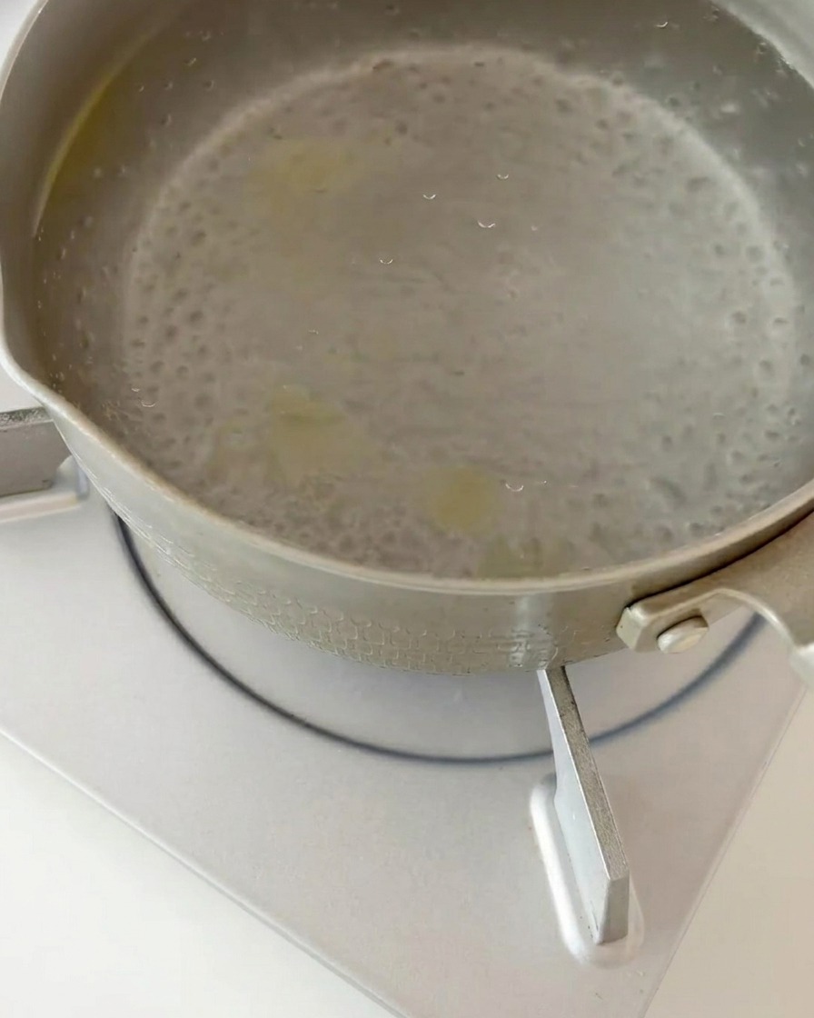 Ugotowany makaron fusilli odcedzany z wrzątku na durszlaku.